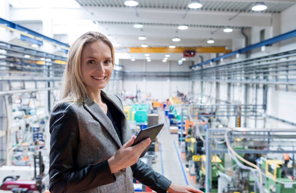 Woman in suit holding a tablet in a modern warehouse