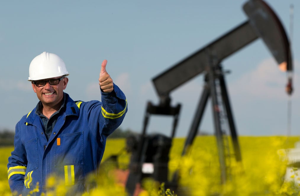 Man with a thumbs up standing in an oil field
